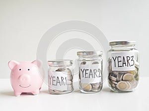 Pink piggy bank with coins in 3 glass bottle, Saving money for future plan and retirement fund concept