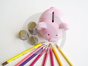 Pink piggy bank with coins pile and Bright colored pencils, Saving money for future plan and retirement fund concept