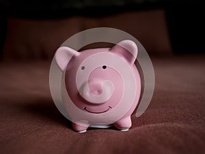 Pink piggy bank on dark red bed background, Saving money for future plan and retirement fund concept
