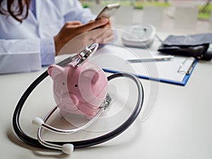 Pink piggy bank with doctor stethoscope and pressure gauge, Saving money for future plan and Health insurance concept