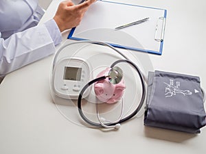 Pink piggy bank with doctor stethoscope and pressure gauge, Saving money for future plan and Health insurance concept