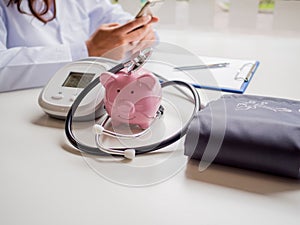 Pink piggy bank with doctor stethoscope and pressure gauge, Saving money for future plan and Health insurance concept