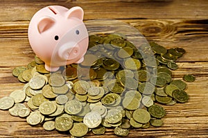 Pink piggy bank on heap of coins on wooden background. Saving money concept