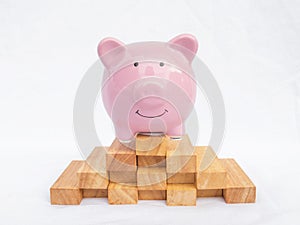 Pink piggy bank isolated on white background with wooden block, Saving money for future plan and retirement fund concept