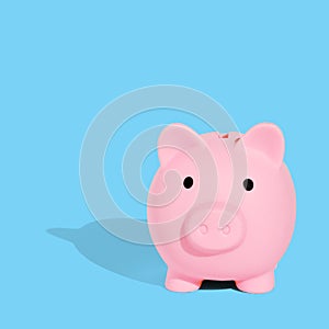 . The pink piggy bank is photographed against a light blue background with hard shadows. Safe savings concept. Creative idea