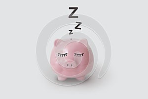 Pink piggy bank pictured sleeping on gray background