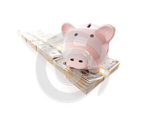 Pink Piggy Bank on Row of Hundreds of Dollars Stacks Isolated on a White Background photo