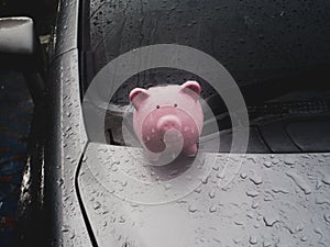 Pink piggy bank standing on the car with rain. despite obstacles Saving money for future plan and retirement fund concept