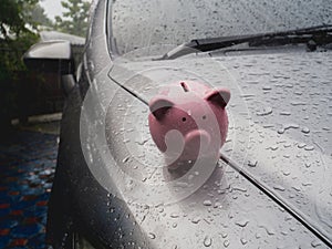 Pink piggy bank standing on the car with rain. despite obstacles Saving money for future plan or saving money with car insurance