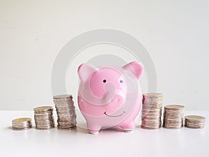 Pink Piggy bank standing between coins bar graph, Saving money for future plan and retirement fund concept
