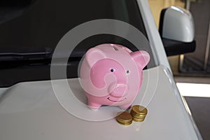 Pink piggy bank standing on the white car, saving money for new car or saving money with car insurance