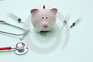 Pink piggy bank with stethoscope and syringe