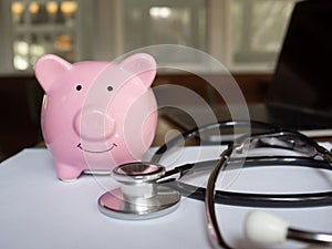Pink piggy bank and stethoscope on wooden table, to demonstrate for saving money for future. Financial Health concept