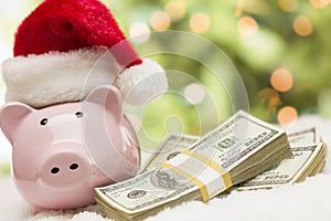 Pink Piggy Bank Wearing Santa Hat Near Stacks of Money on Snowflakes