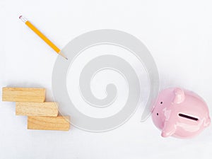 Pink piggy bank on white background with wooden block and yellow pencil, Drawing own way to saving money for future plan