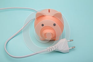 Pink piggy bank and white cord, power savings concept