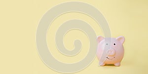 Pink piggy bank on yellow background with copy space, saving and investing Financial management and bank