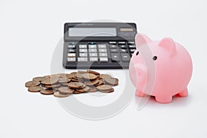 Pink piggy or coin bank or piggybank or money box, coins and calculator - finance and savings concept on white