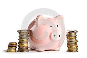 Pink piggybank near coins stacks isolated on white background. Business or finance concept