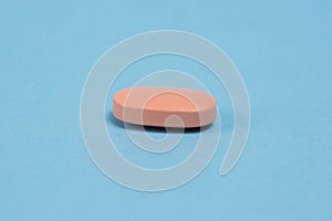 Pink pill macro on blue paper background with copy space