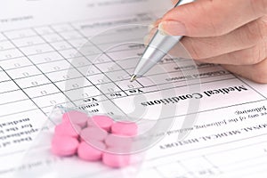 Pink pills and hand writing on medical questionnaire form