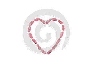 Pink pills in the shape of a heart on a white isolated background. Daily Vitamins dose. Heart shape made of tablets for