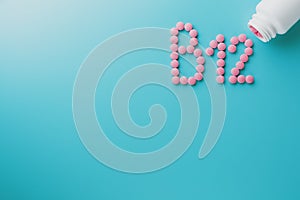 Pink pills in the shape of the letter B12 on a blue background, spilled out of a white can, low contrast