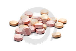 Pink pills on a small heap isolated with shadows on a white back