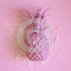Pink pineapple lying in party glitters. Concept minimal photo. Top view