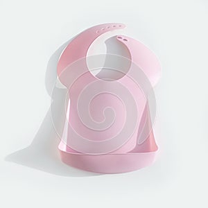 Pink plastic baby bib on white background with shadow. Mockup, top view. Square photography
