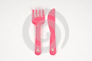 Pink plastic baby fork and knife on a white background