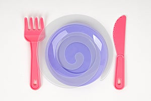 Pink plastic baby pink fork ,knife and plate on a white background isolated