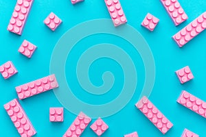 Pink plastic building blocks on turquoise blue background with copy space