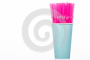 Pink plastic drinking straws in blue disposable cup isolated on white background