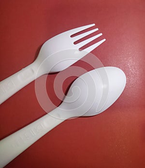 Pink plastic spoon and fork cutlery, isolated on red background