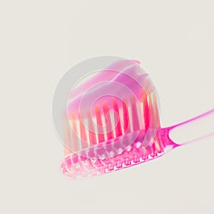 Pink plastic toothbrush with strawberry toothpaste on an isolated background