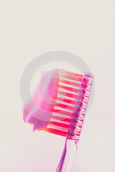 Pink plastic toothbrush with a white toothpaste on an isolated background