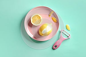 Pink plate with lemon and zester on color background