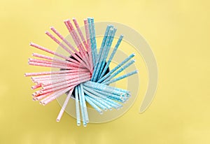 Pink polka dot paper straws and light blue polka dot paper straws on yellow background. Drinking straws
