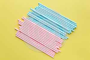 Pink polka dot paper straws and light blue polka dot paper straws on yellow background. Drinking straws,