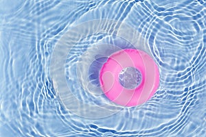 Pink pool float ring floating in a refreshing blue swimming pool. Top view