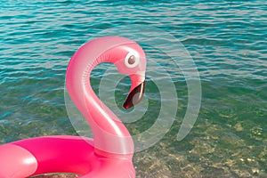 Pink pool. Pink inflatable flamingo in blue sea water on summer ocean beach background. Pool float party