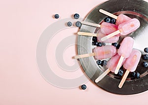 Pink popsicles with blueberries on a tray