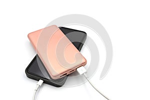 Pink power bank is connected by cable to the phone on a white background. Charging your phone from a power bank
