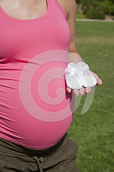Pink pregnant with bootees in hand
