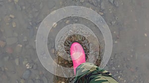 Pink puddle. Rain bright boots. Dirty safety shoes. Summer weather. Walking