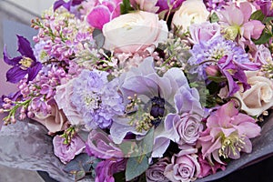 Pink purple blue wedding bouquet by florist with different flowers and roses close-up. Floral background