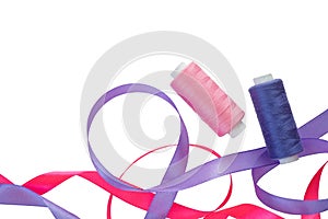 Pink and purple curly satin ribbons, spools of pink and purple thread on a white. Horizontal banner with two satin ribbons and