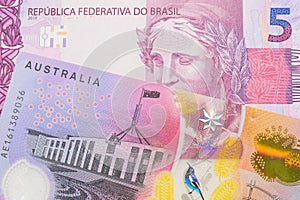 A pink and purple five real bank note from Brazil paired with a colorful five dollar bill from Australia.