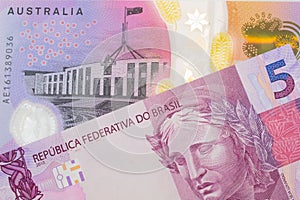 A pink and purple five real bank note from Brazil paired with a colorful five dollar bill from Australia.
